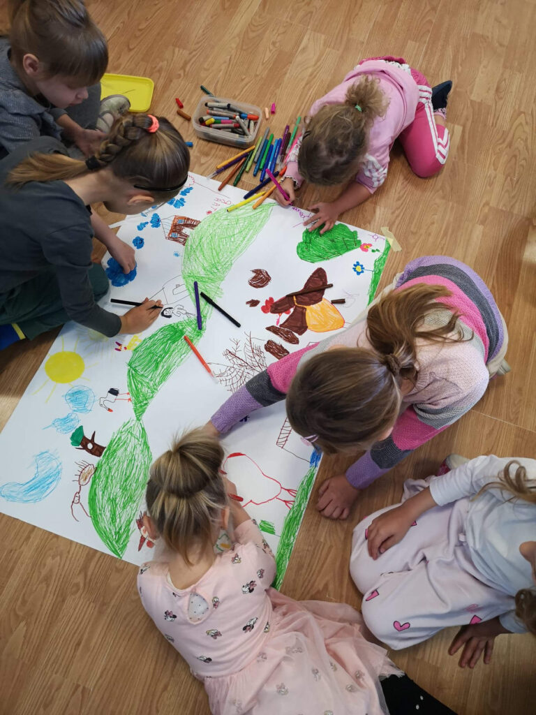 Djeca zajednički crtaju i bojaju s bojicama krajolik