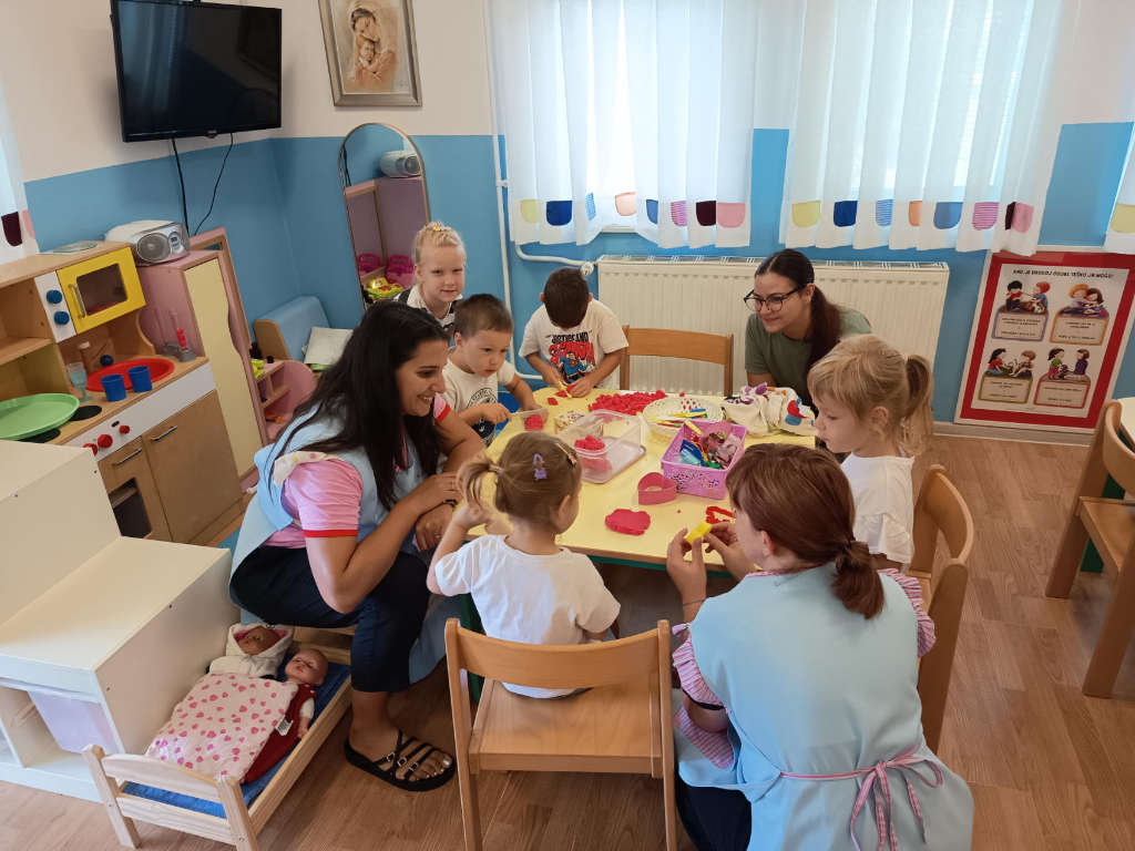 Odgojitelji i djeca u vrtiću za stolom